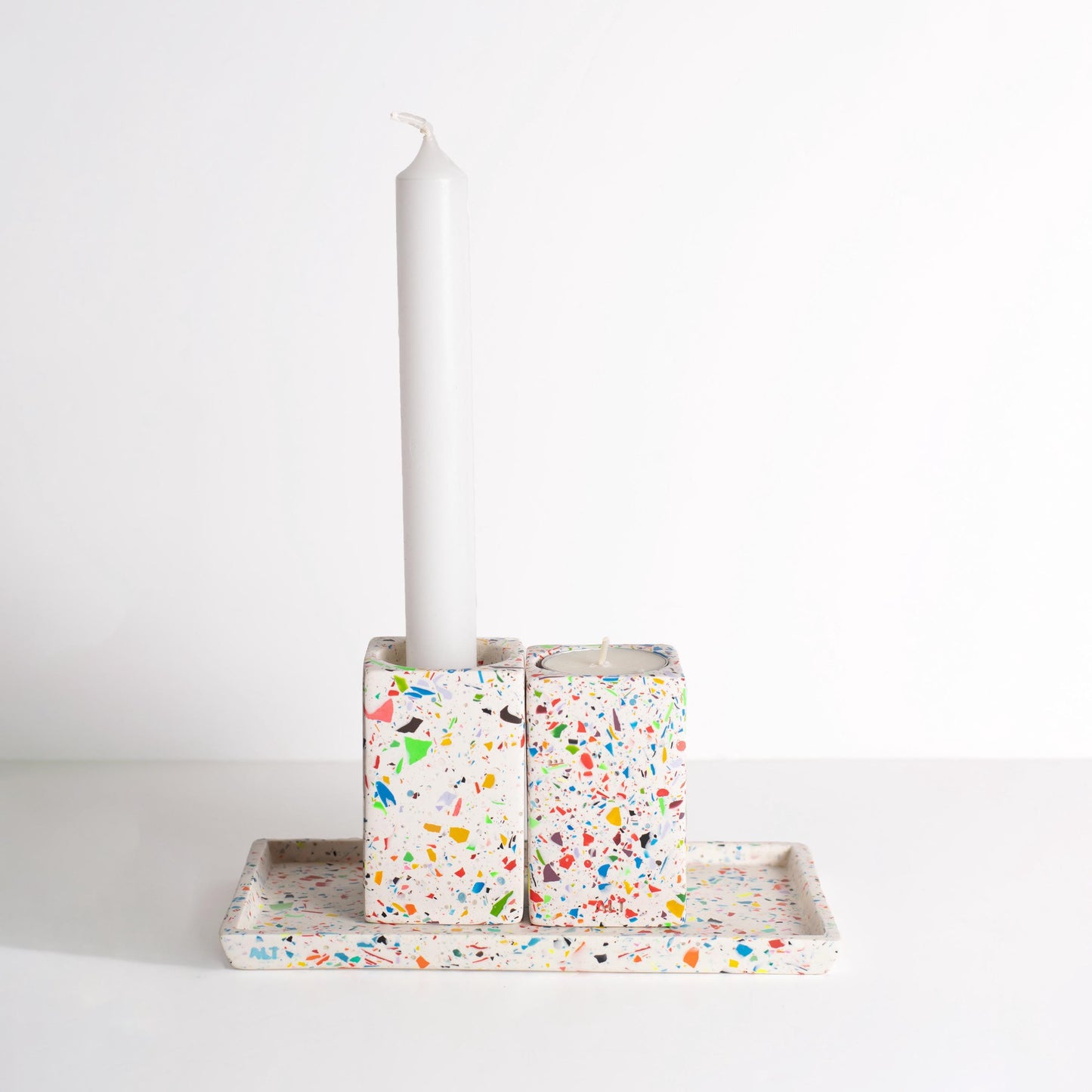 Decorative rainbow confetti candle holders on a rainbow confetti rectangular tray on a white background