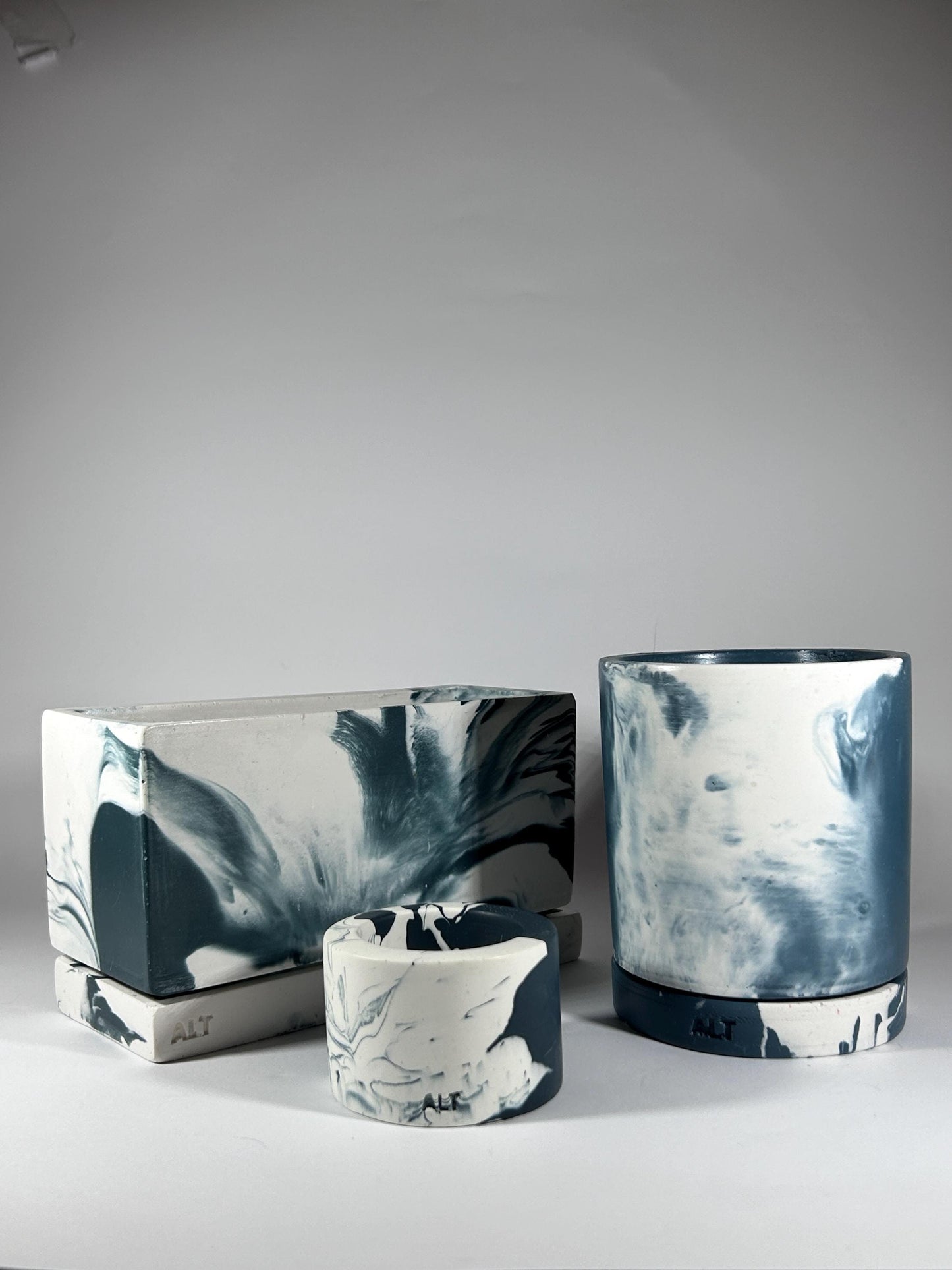 Set of three navy marbled ceramic containers on a grey background