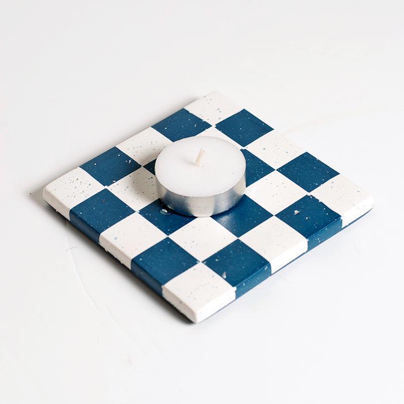 Checkerboard patterned coaster with a candle on a white background