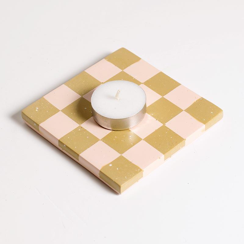 Checkered pink and beige coaster with a candle on a white background