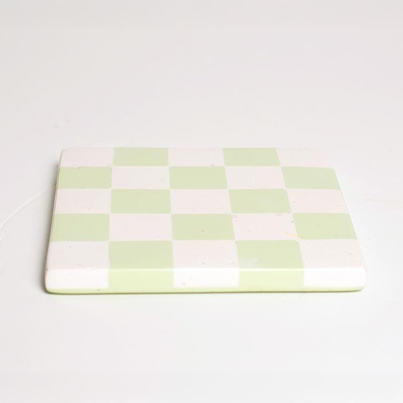 Mint green and white checkered coaster on a white background