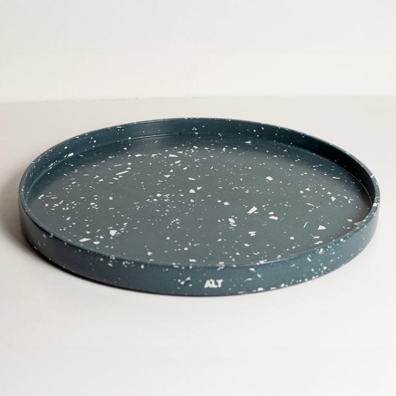 Round navy terrazzo tray on a light grey background