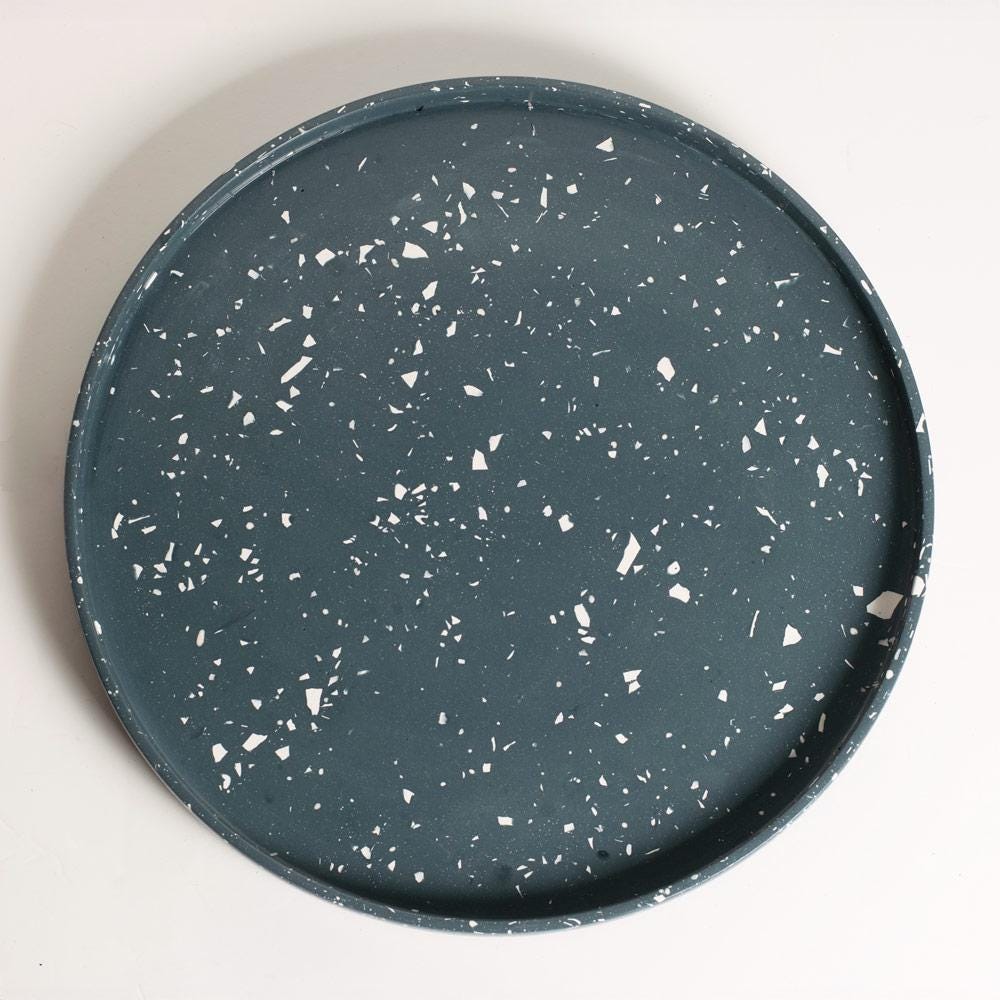 Round navy terrazzo tray on a light grey background