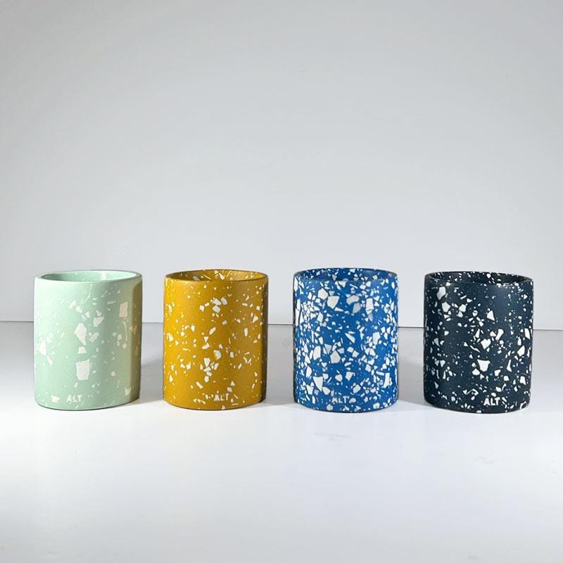 Four speckled pen pots in green, yellow, blue, and black on a white background