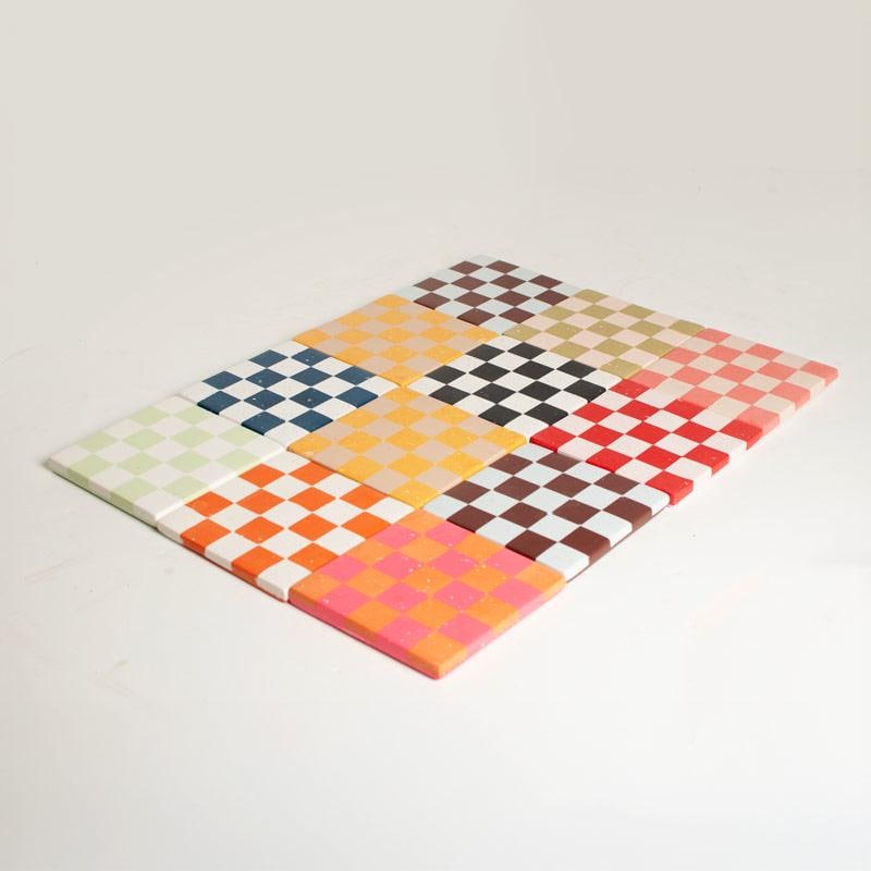 Colourful checkered pattern of square coasters on a white background
