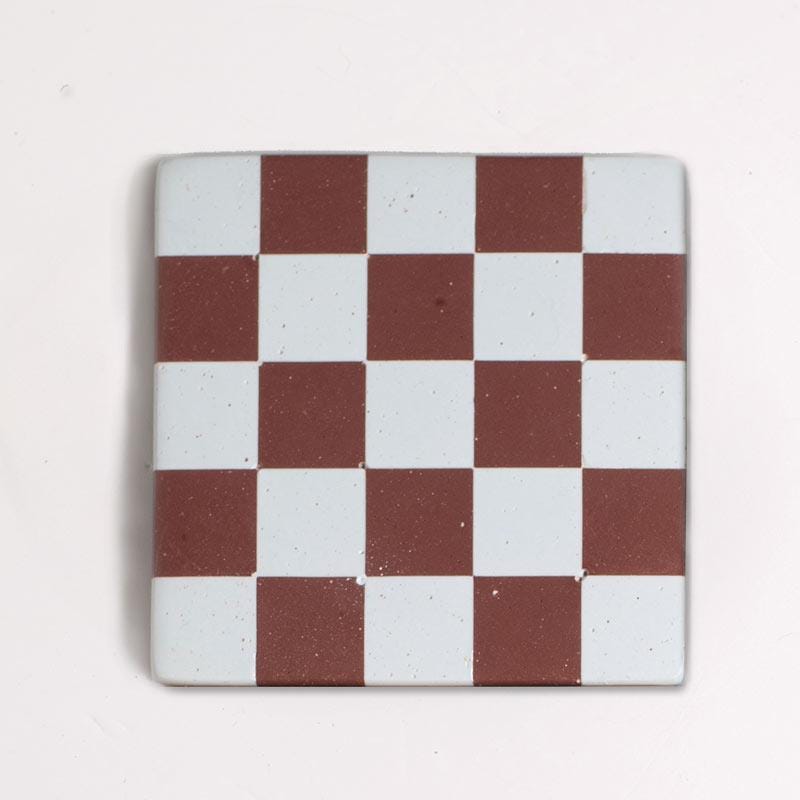 Brown and light blue checkered coaster on a light grey background