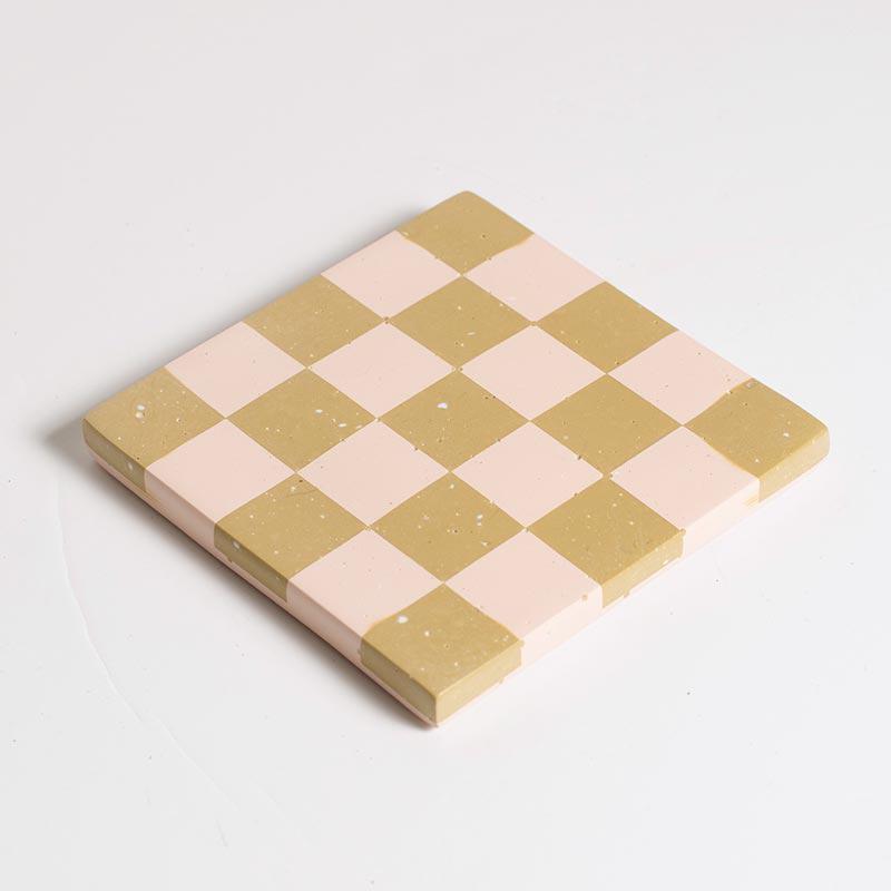 Checkered pink and beige coaster on a white background