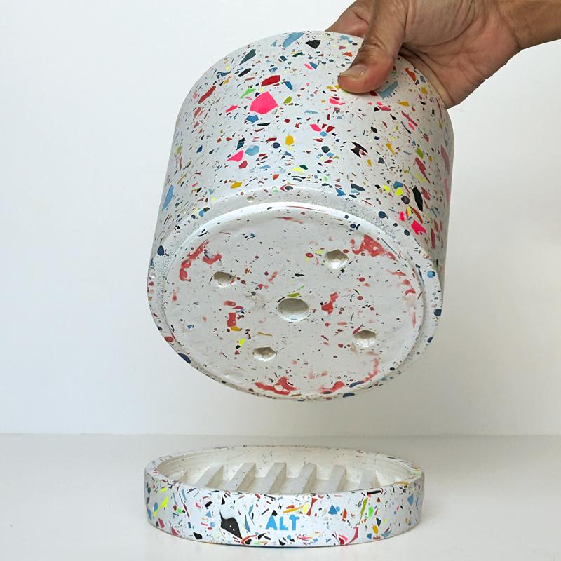 Hand holding a colourful rainbow terrazzo pot on a white background