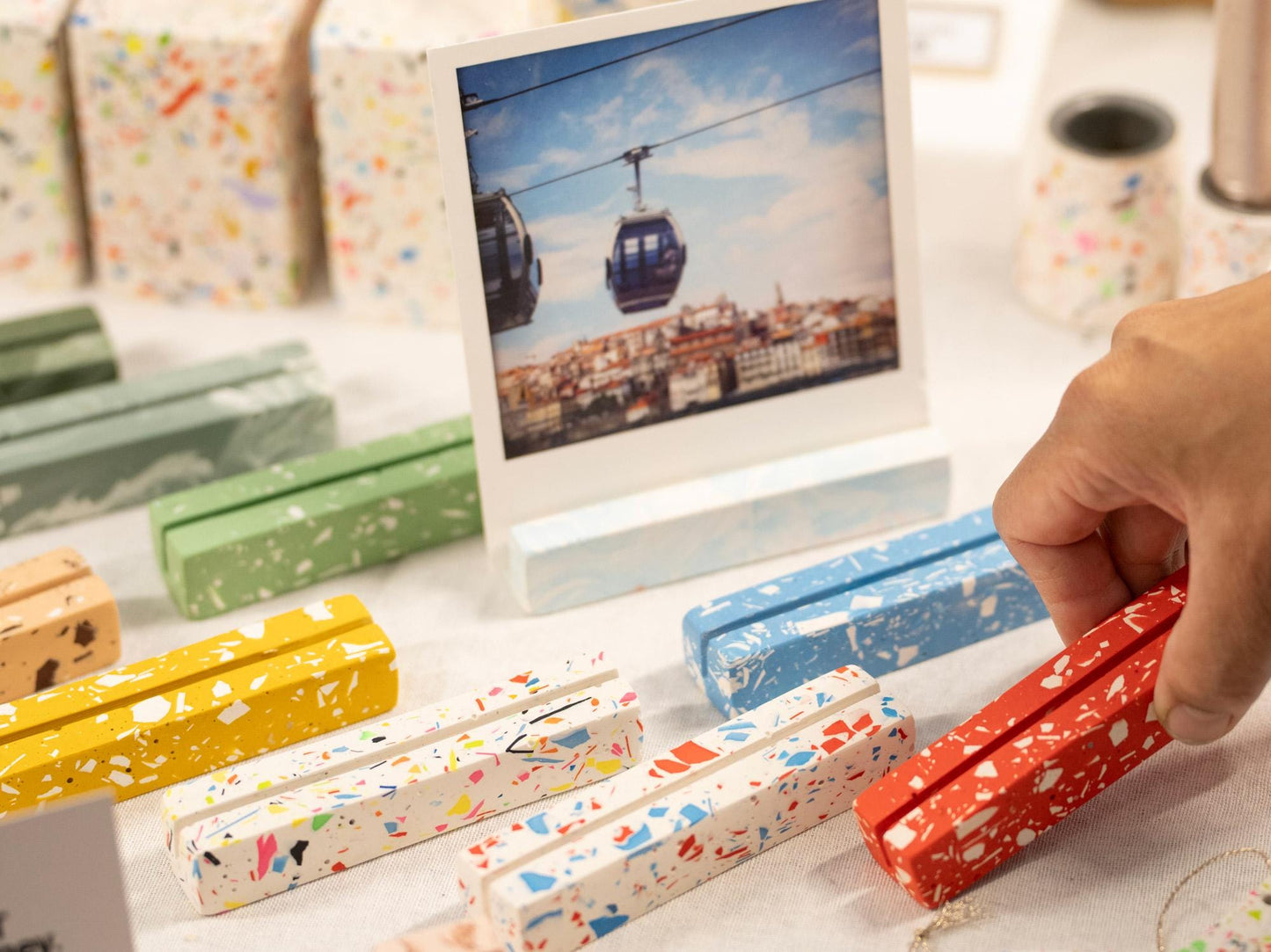 Colorful paper boxes with a hand selecting one, a photo frame in the background.