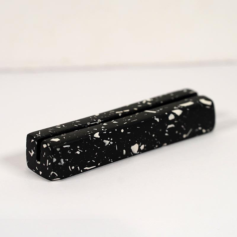 Black and white speckled rectangular object on a light gray background