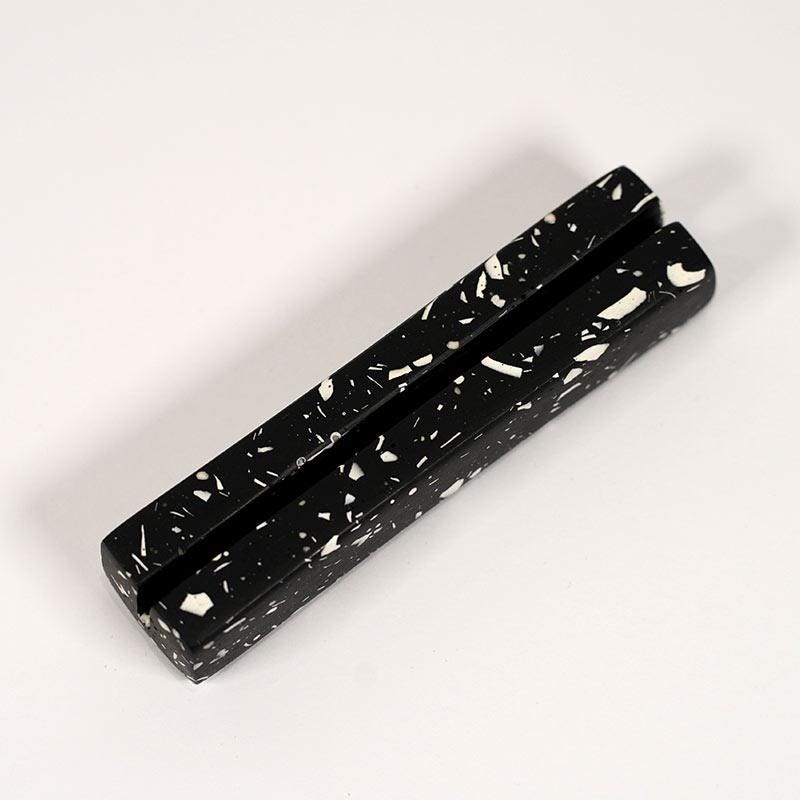Black rectangular object with white speckles on a white background