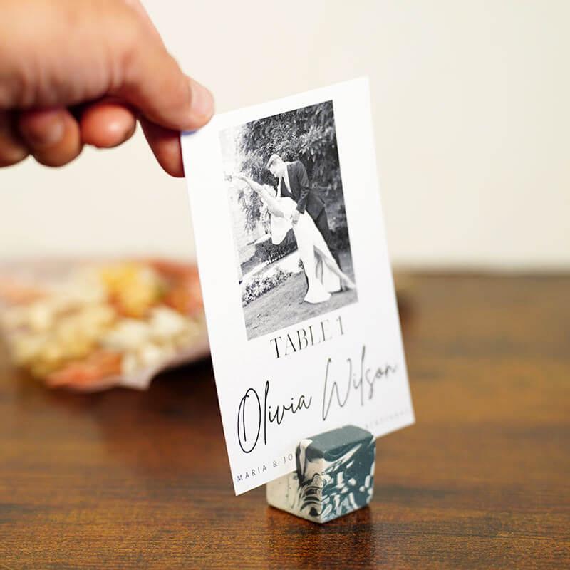 Hand holding a photo card with a couple on a wooden surface