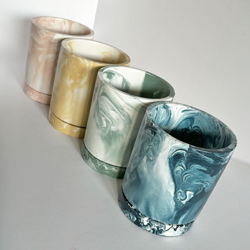Four Marbled planters with a drainage hole and separate water trays with 'ALT' branding on a light gray background