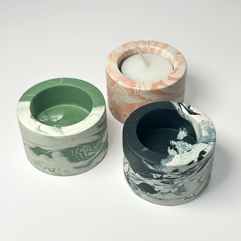 Three marbled-patterned candle holders with a candle on a white background