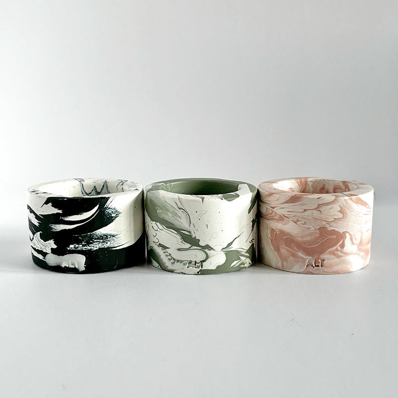 Three marbled-patterned candle holders on a white background