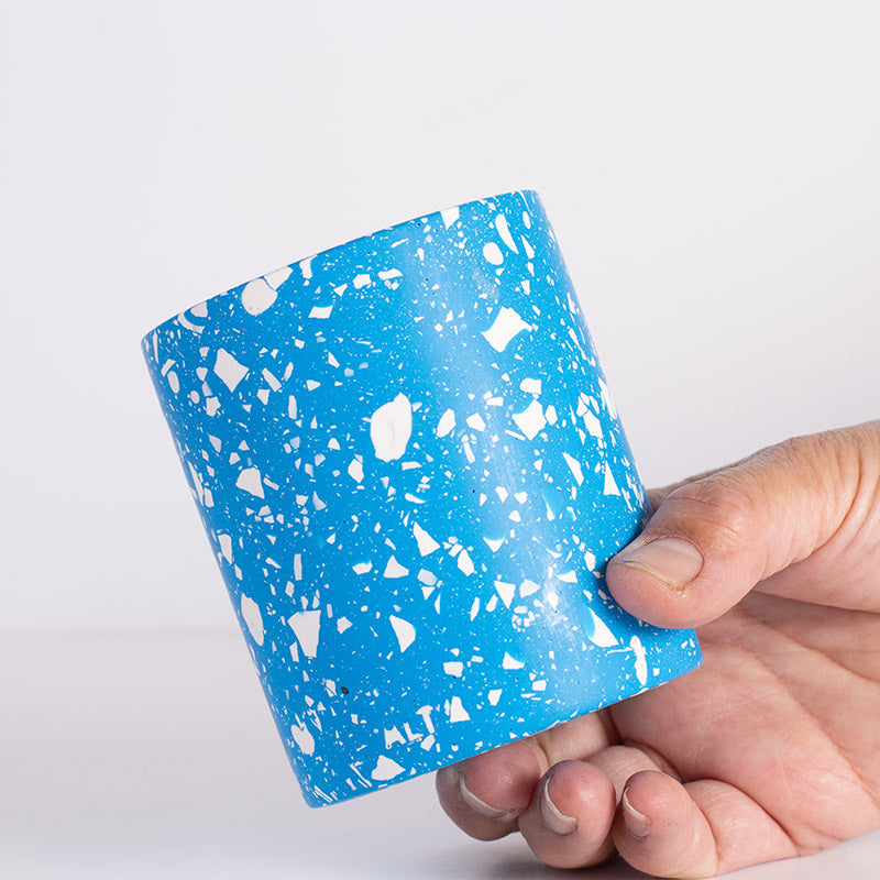 Hand holding a blue and white terrazzo pencil holder against a light gray background