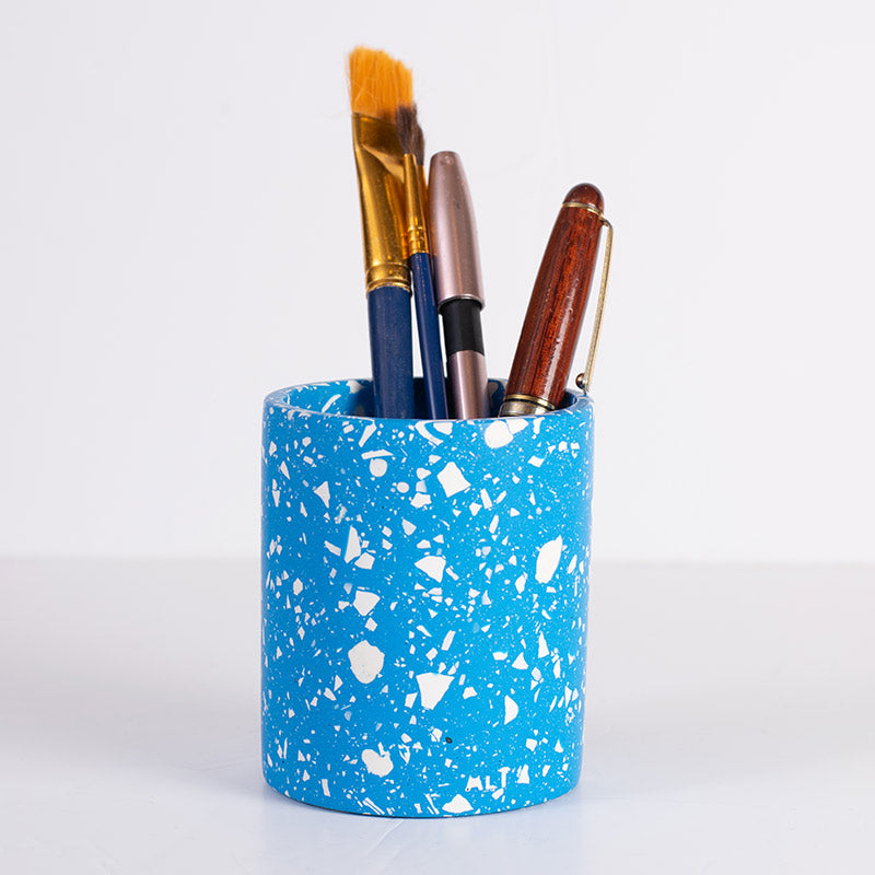 Blue terrazzo pen holder with various pens on a white background