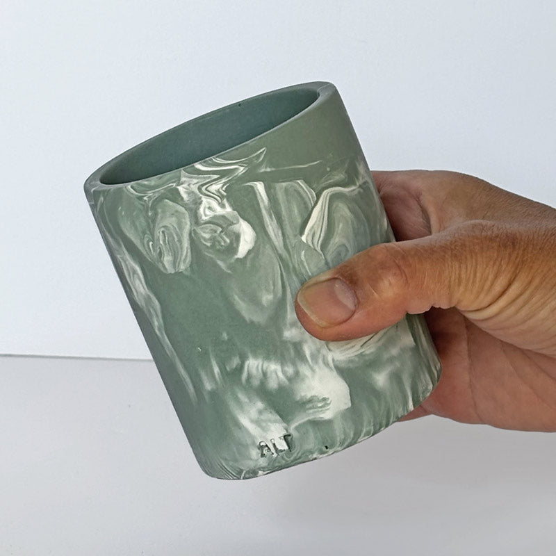 Hand holding a Marble-patterned Moss Green pen pot with 'ALT' branding against a white background