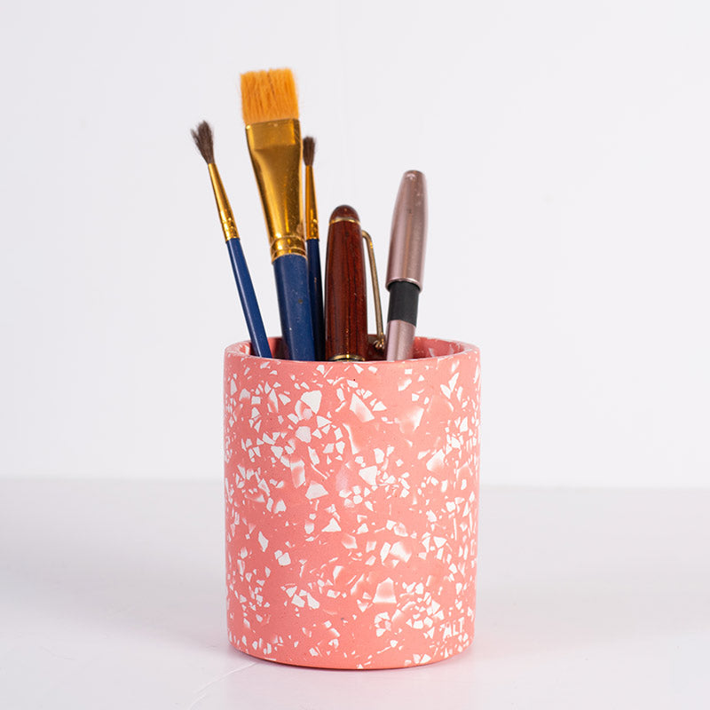 Pink terrazzo pen holder with various pens on a white background