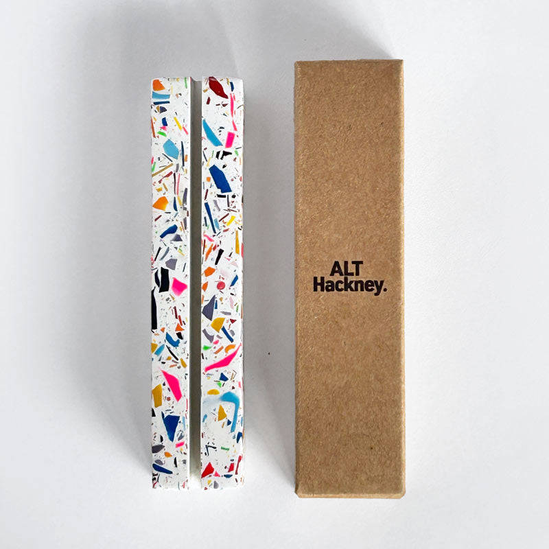 Rectangular rainbow terrazzo photo holder and an eco brown box with 'ALT Hackney.' branded logo, on a white background.