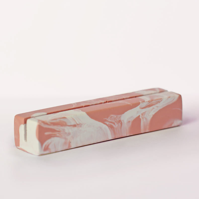 Marble-patterned salmon pink and white photo holder on a white background