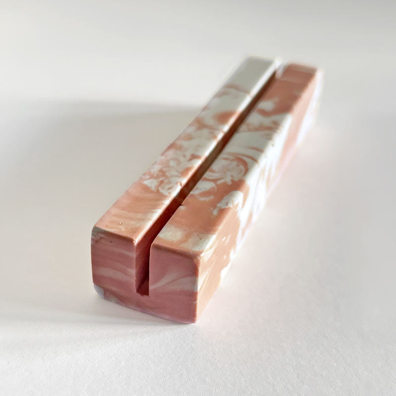 Marble-patterned salmon pink and white photo holder on a white background