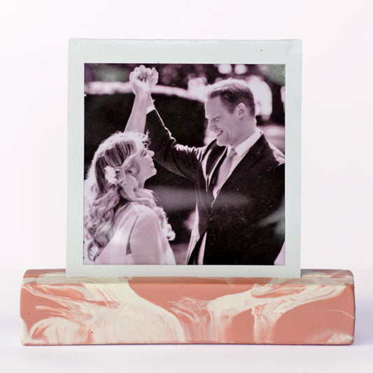 Marble-patterned salmon pink and white photo holder with a black and white photo of a couple on top