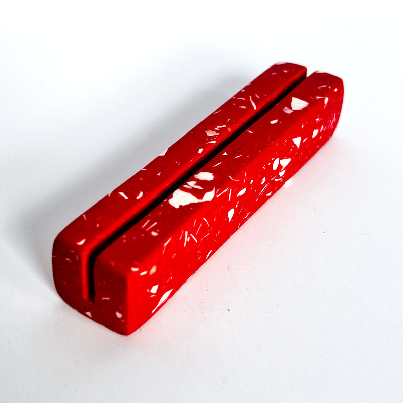 Red rectangular object with white speckles on a white background