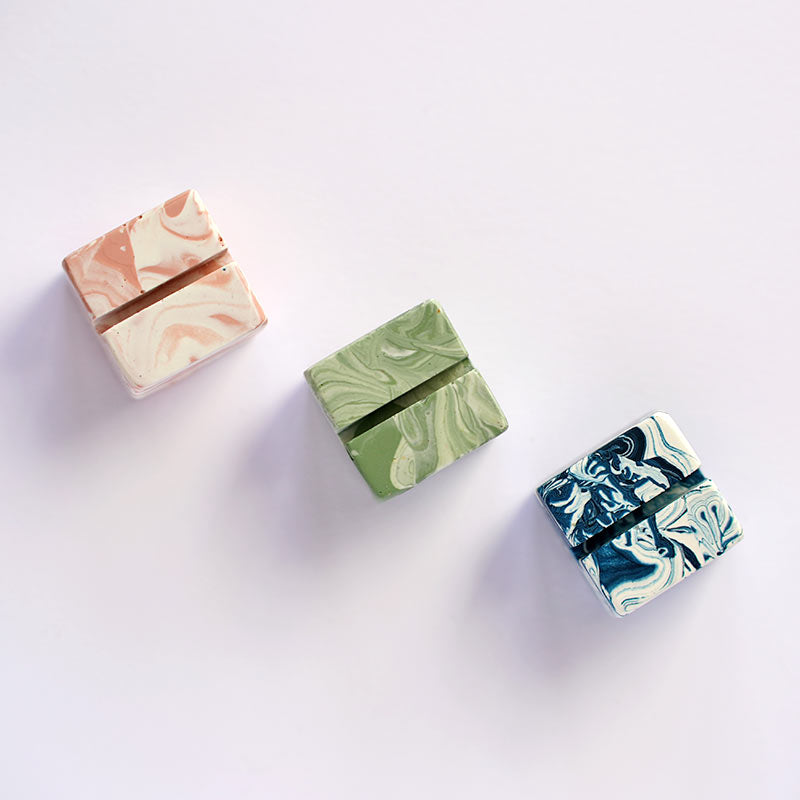 Three small square marble-patterned photo holders on a white background