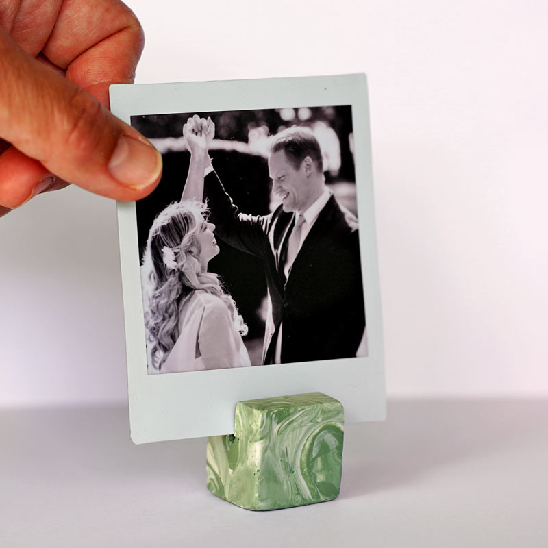 Hand holding a Moss Green marble patterned photo holder on a white background