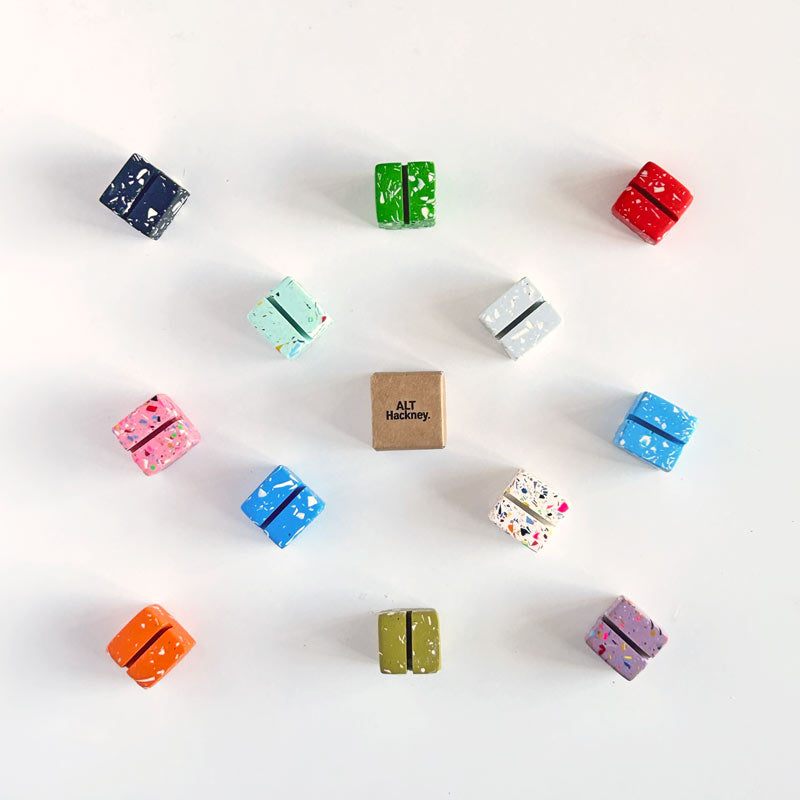 Assorted colourful small cube-shaped terrazzo photo holders on a white background