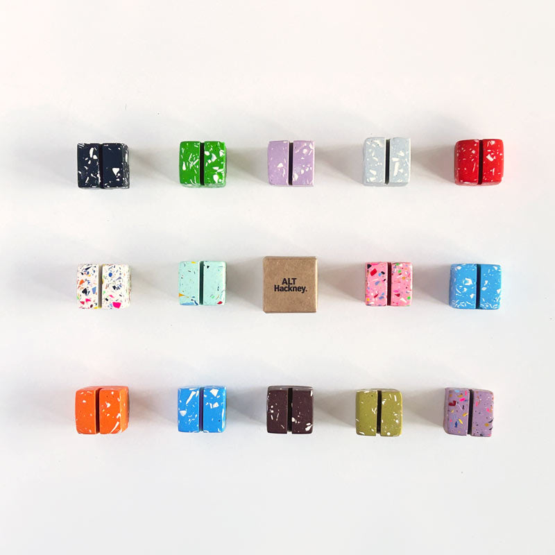 Assorted colourful small cube-shaped terrazzo photo holders on a white background