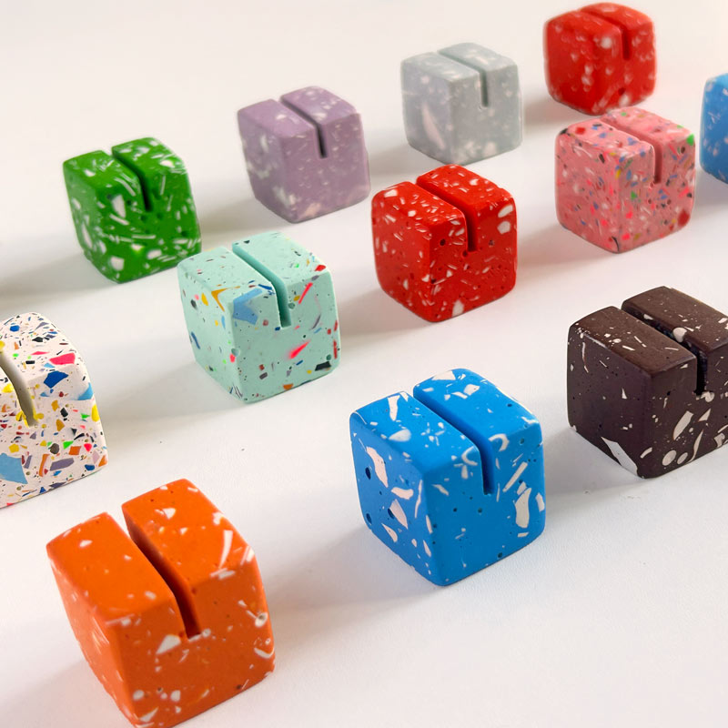Assorted colourful cube-shaped photo holders on a white background