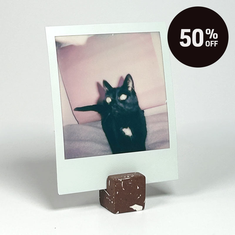A small cube-shaped photo holder with a brown terrazzo pattern featuring white flecks, shown on a light gray background with a black circular '50% OFF' badge in the top right corner.