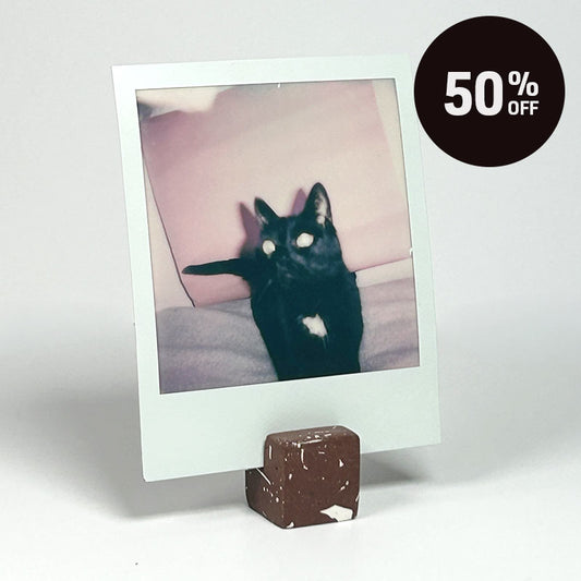 A small cube-shaped photo holder with a brown terrazzo pattern featuring white flecks, shown on a light gray background with a black circular '50% OFF' badge in the top right corner.