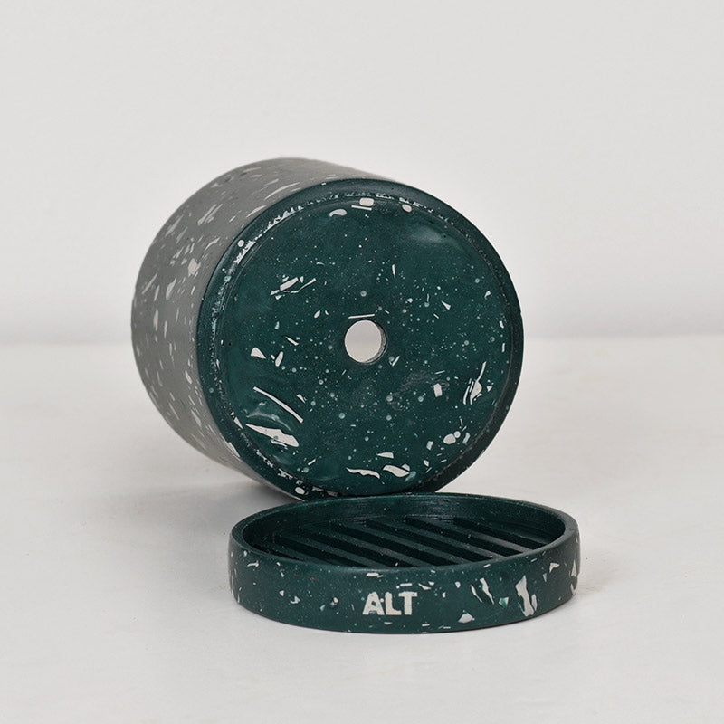 A dark green and white speckled plant pot with its lid placed in front, showing the word 'ALT' on the lid. The container is photographed on a clean, light gray studio background.