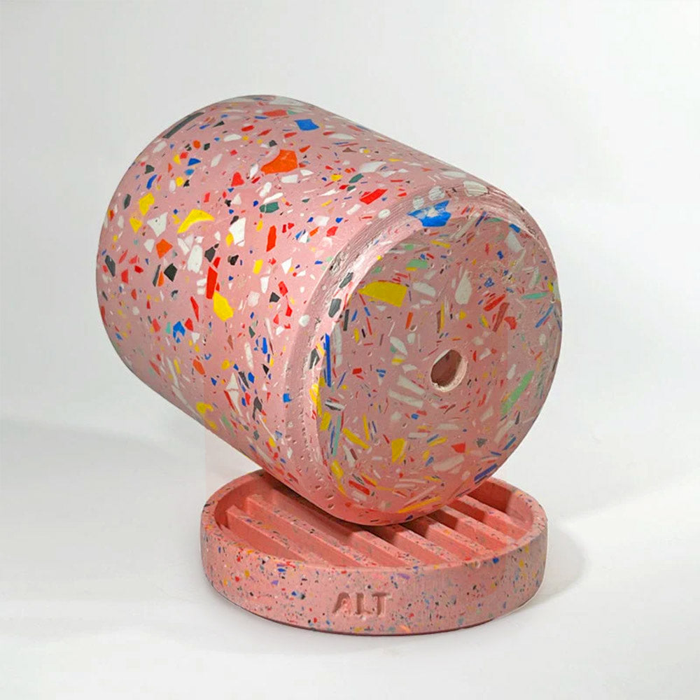 A pink terrazzo-patterned plant pot with a drainage hole and a separate water tray against a clean white studio background.