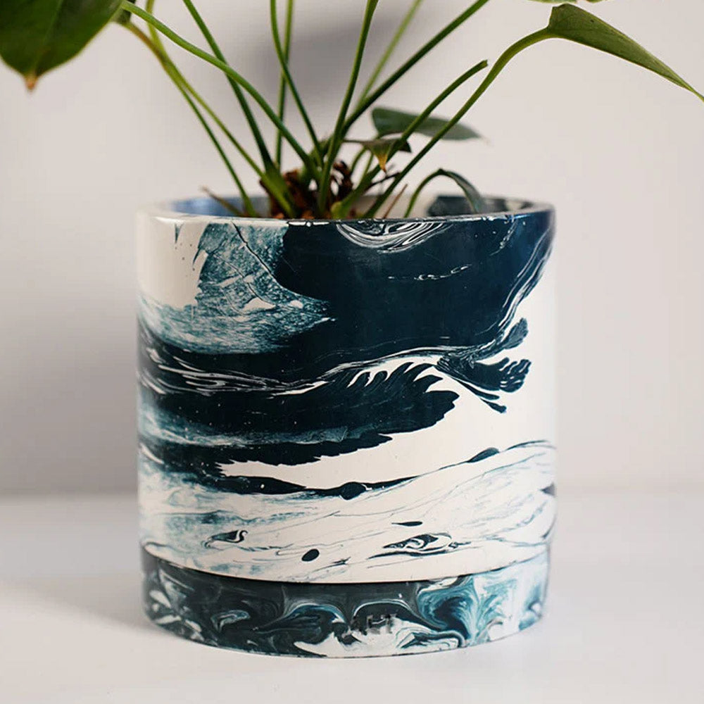 Navy marble-patterned plant pot with a plant on a white background