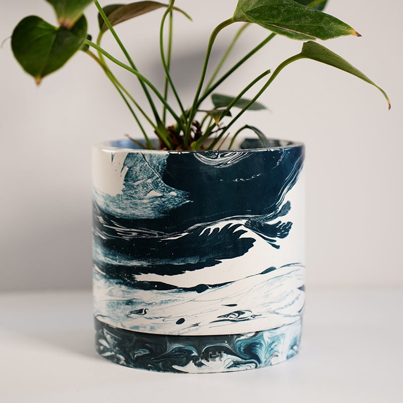 Navy marble-patterned plant pot with a plant on a white background