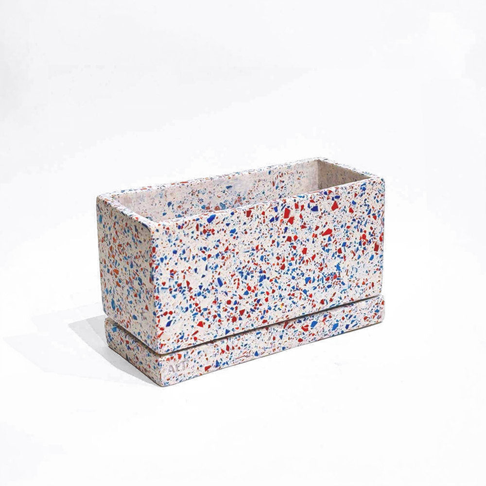 Rectangular planter with red, blue, and white terrazzo with drainage holes and a water tray on a white background
