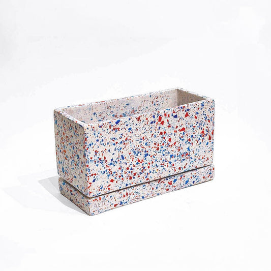 Rectangular planter with red, blue, and white terrazzo with drainage holes and a water tray on a white background