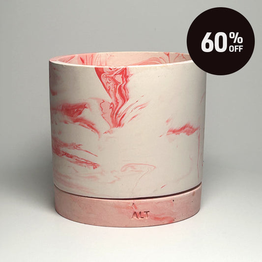 A cylindrical planter pot with a pink and white marbled design, featuring a matching marble-patterned base and  small drainage holes. A black circular '60% OFF' promotional sticker is in the top right corner.