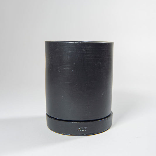 Black Jesmonite plant pot with a separate water tray on a light gray background