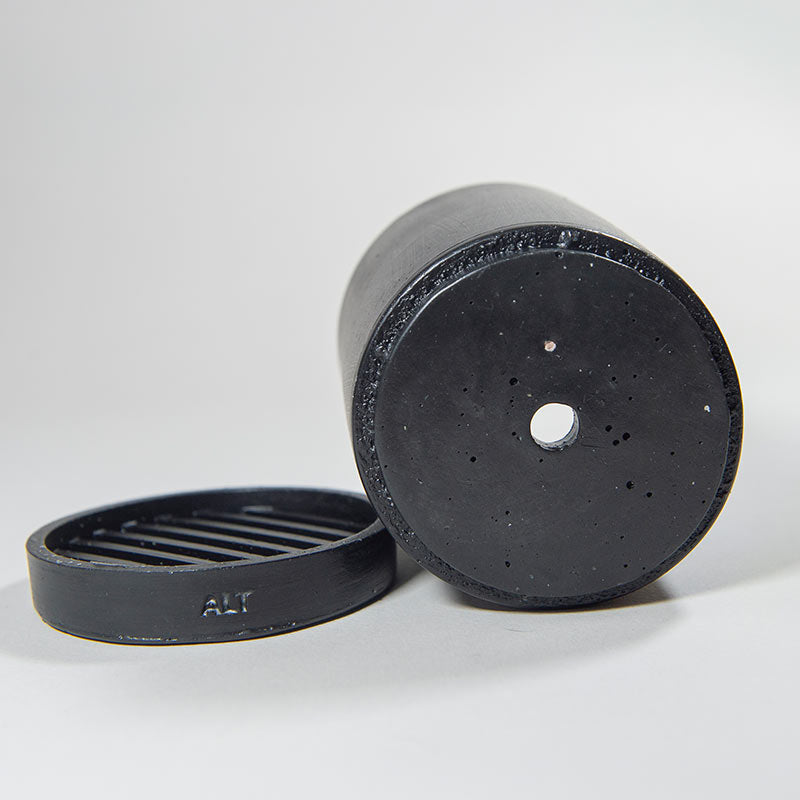 Black Jesmonite plant pot with drainage hole and a separate water tray on a light gray background