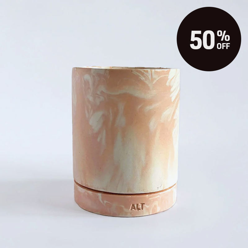 A marbled salmon pink planter with a drainage hole and a water tray with 'ALT' branding on a light grey background. A black circular '50% OFF' promotional sticker is in the top right corner.