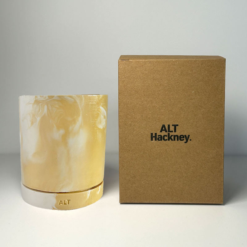 Marbled beige and white plant pot with drainage hole and a water tray next to a brown box labeled 'ALT Hackney' on a gray background