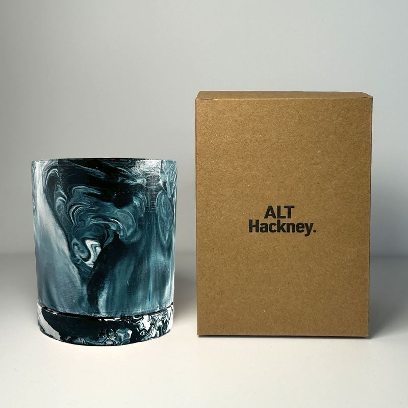 Navy marbled navy and white plant pot with a drainage hole and a water tray next to a brown box labeled 'ALT Hackney' on a neutral background