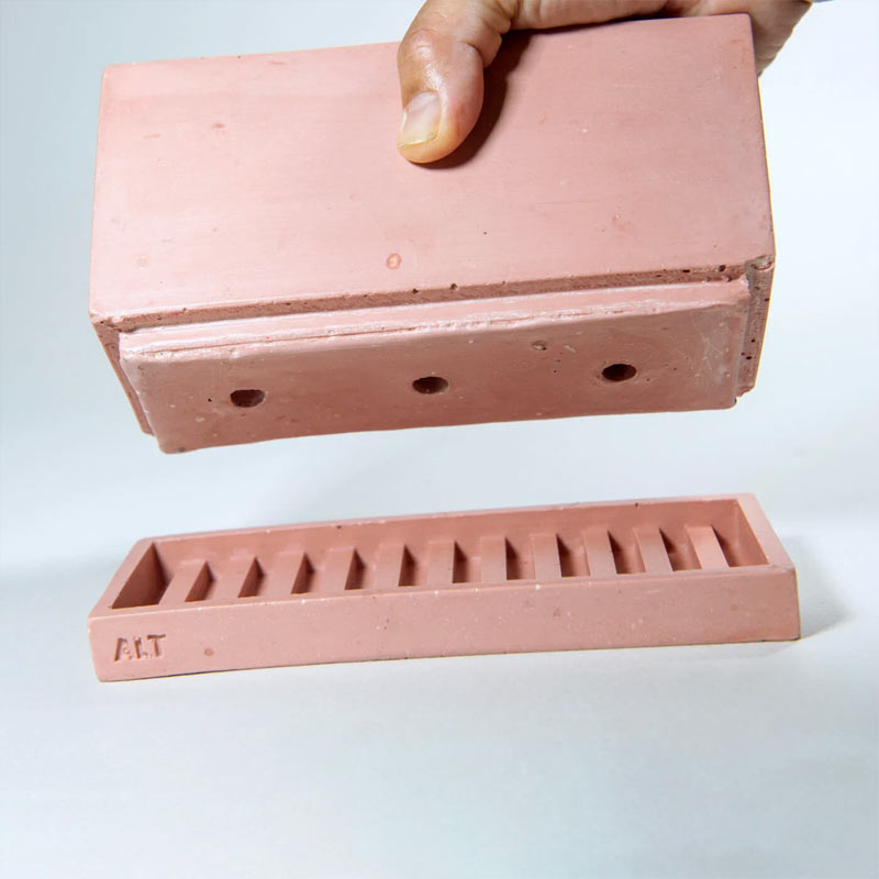 A dusty rose coloured rectangular plant pot, three drainage holes, and a raised edge, shown floating above a matching saucer with a slotted channel. A hand is holding the main planter.