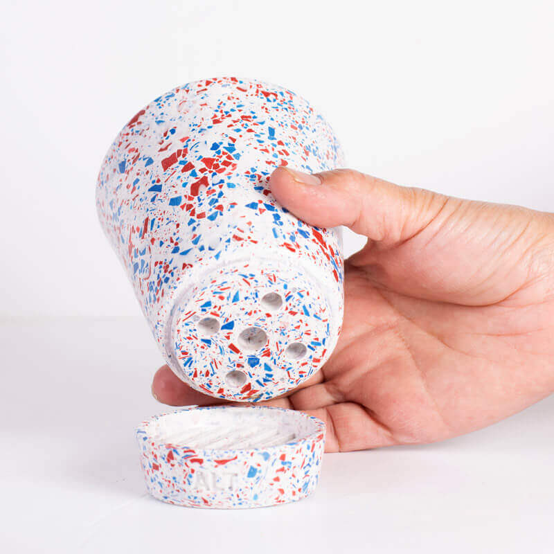 Hand holding a Red and Blue terrazzo plant pot with drainage holes and a water tray 