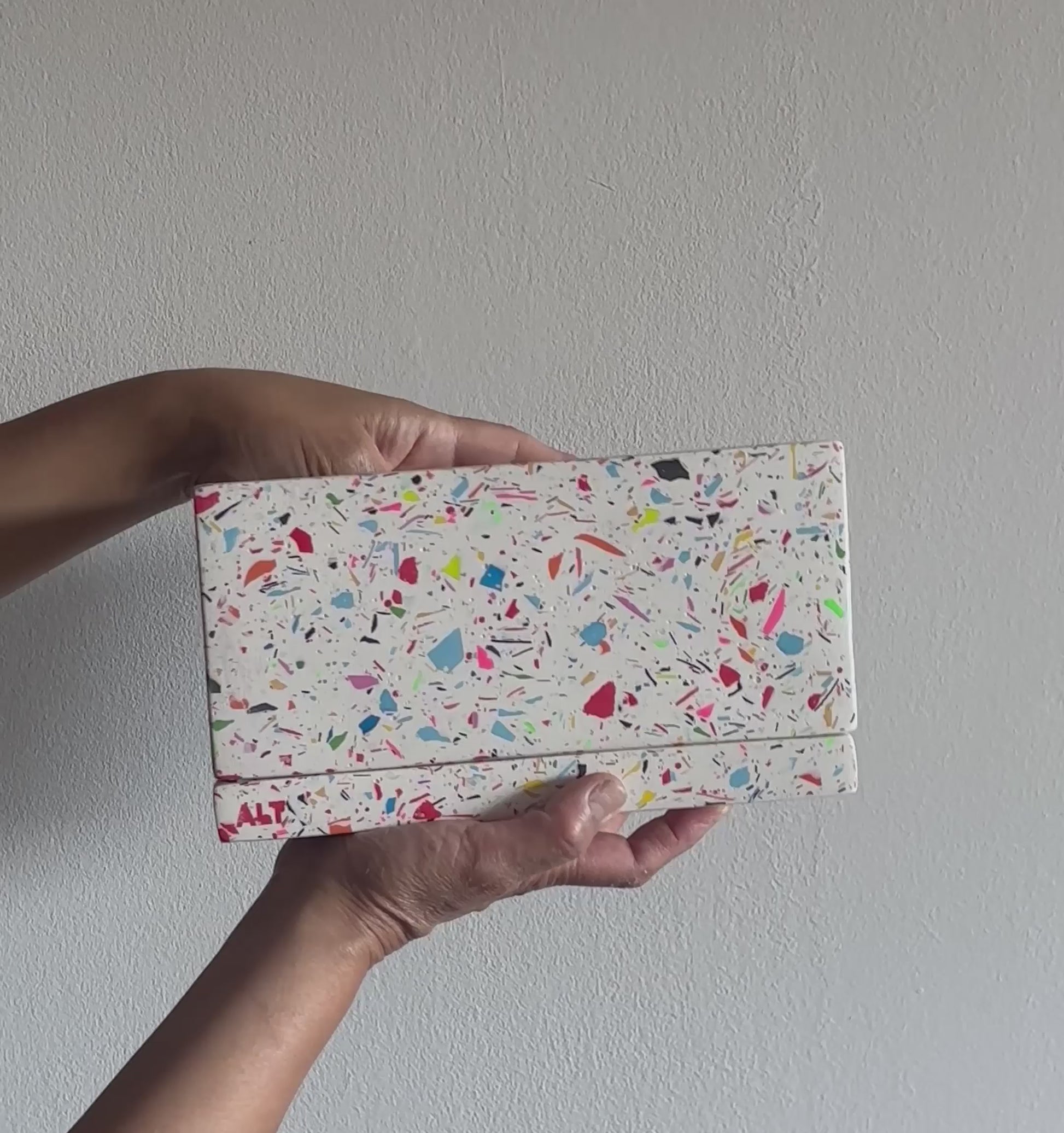 Hands holding a Large Rectangular Rainbow Terrazzo Jesmonite Plant Pot with Drainage holes & Saucer on a white background 